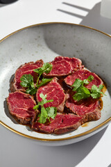 Gourmet Beef Tataki on Ceramic Plate with Fresh Herbs and Minimalist Lighting