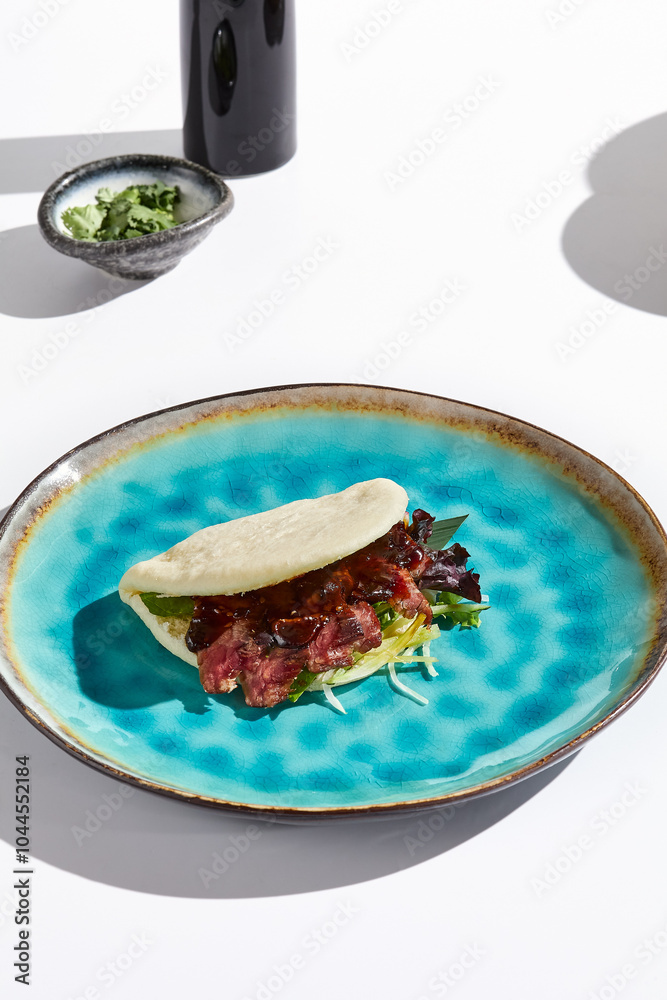 Wall mural Bao Bun with Marbled Beef on Vibrant Plate Minimal Still Life in Natural Light