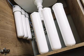 Home water filtration plant close-up. Small water filters under the sink in the kitchen