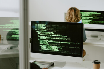 Unrecognizable cybersecurity department specialists coding and upgrading systems on modern desktop...