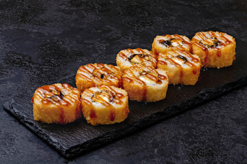 Japanese sushi, rolls fried tempura with unagi sauce on black background