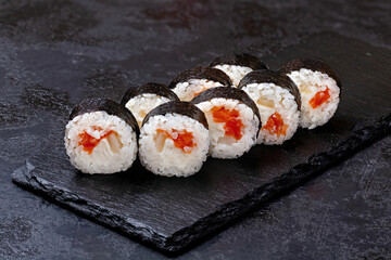Japanese sushi rolls with salmon and cream cheese in nori seaweed on black background