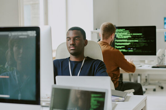 Young African American man working on desktop computer at workplace in modern leading IT company office