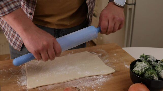 a man rolls out dough on a wooden board