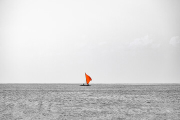 Monochrome Ocean Photograph with a Small Red Sailing Boat

