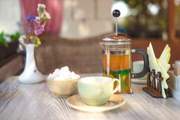 Tranquil afternoon tea setup with fresh herbs, sugar, and blooming flowers in a cozy café