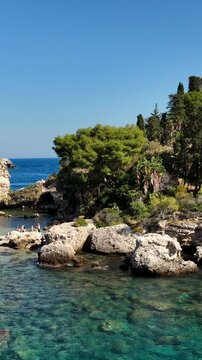 Il mare e la spiaggia di Isola Bella a Taormina, Sicilia, sud Italia.
Ripresa aerea della baia di Taormina con l'Isola Bella collegata alla terra ferma tramite un istmo di terra.