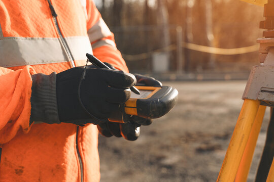 Urban construction worker measuring site with a handheld device during the golden hour