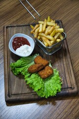 Chicken Nuggets, French Fries, and Dipping Sauces on Wooden Board