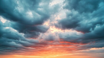 Fototapeta premium A dramatic sky filled with dynamic clouds displays hues of orange and blue during sunset.