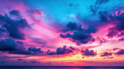 Obraz premium A vibrant sunset paints the sky with shades of pink, purple, and blue, reflecting beautifully over a calm ocean horizon.