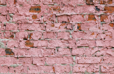 A pink brick wall with a lot of cracks and holes