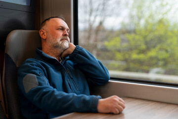 Thoughtful traveler gazing out the train window on a serene journey through the countryside in...