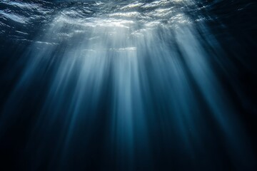 Obraz premium Sunbeams pierce through the ocean surface, creating a dramatic underwater scene.