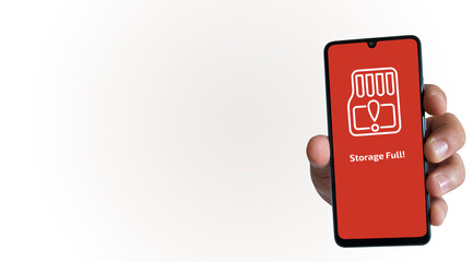 A hand holding a smartphone and a “Storage Full” warning on the phone screen. Device storage space. Close-up. Empty text field, high resolution.	
