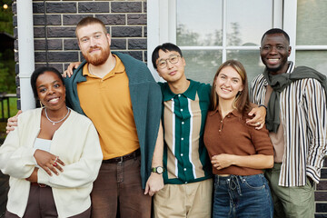 Colorful waist up portrait of happy adult friends posing together smiling at camera standing outdoors and enjoying party at terrace