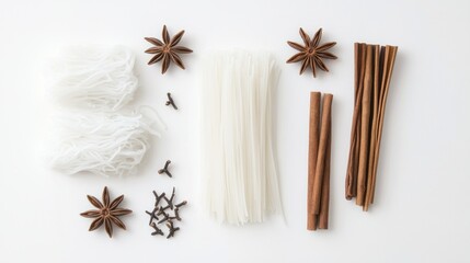 Fototapeta premium Flat lay of essential Asian spices including star anise, cinnamon sticks, and Sichuan peppercorns on a white background.