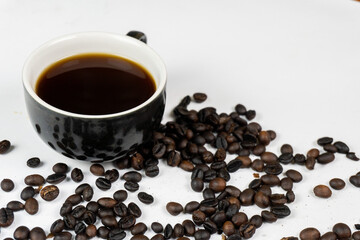 a black cup of coffee and coffee beans on a white background.