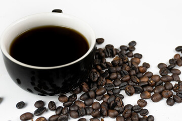 a black cup of coffee and coffee beans on a white background.