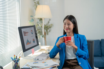 Confident businesswoman at desk, deep in thought, working on project with laptop, charts, and...