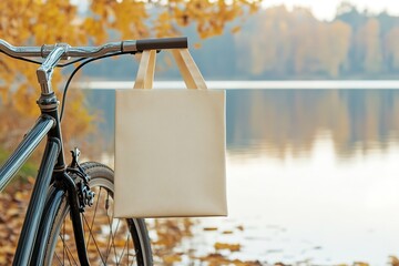 Blank tote bag hanging on bike handlebar, autumn backdrop