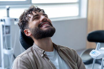 Attractive young man with cheerful smile showing his teeth undergoes orthodontic treatment