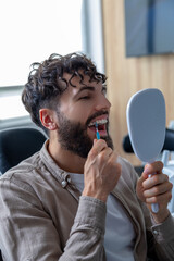 Man with crooked teeth and ceramic braces using dental brush to clean around braces
