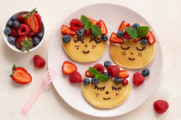 Cute smiling girl face  pancakes with fresh berries