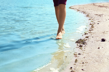 Woman walking barefoot through water on riverbank, closeup