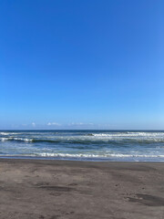 A beach with a clear blue sky and a few clouds