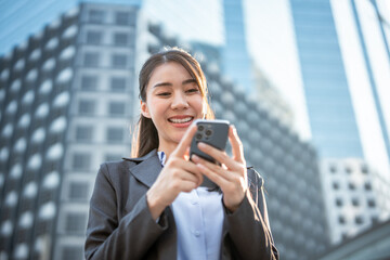 Asian young businesswoman using smartphone while standing in the city. 