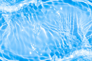 Blue water with ripples on the surface. Defocus blurred transparent blue colored clear calm water surface texture with splashes and bubbles. Water waves with shining pattern texture background.