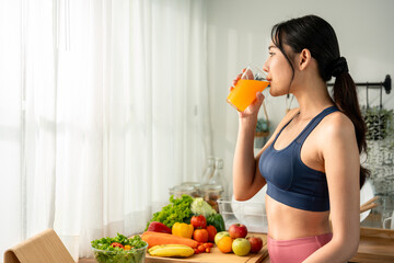 Obraz premium Asian beautiful woman in sportswear drinking orange juice in house. 