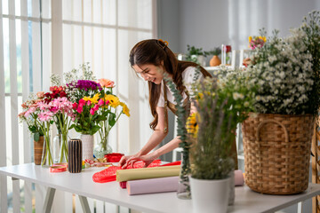 Asian young florist girl completing beautiful bouquet in flower shop.