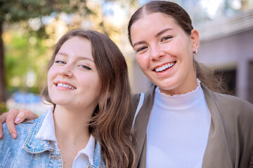 Obraz premium Two Smiling Young Women Posing Outdoors on a Sunny Day