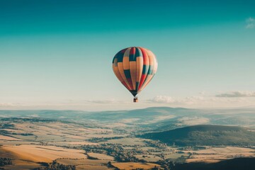 Obraz premium A vibrant hot air balloon floats gracefully above rolling hills. The colorful design adds joy to the scenic view. Perfect for travel and adventure themes. Generative AI