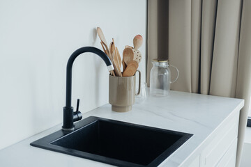 Modern kitchen sink with utensils and minimalist decor in natural light