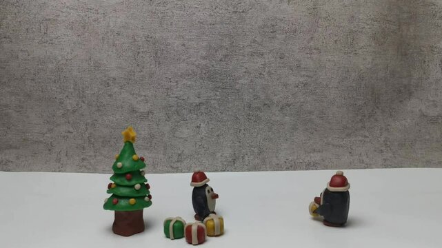 Christmas tree, penguin and, present. A stop-motion Christmas handmade of plasticine. Landscape Background.
