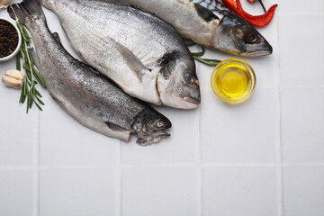 Sea food. Different types of raw fish and products on white tiled table, flat lay. Space for text