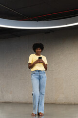 Cheerful African American using mobile phone in indoor modern building