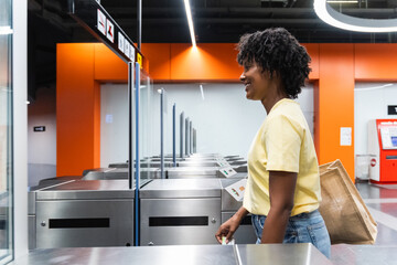 Young afro woman scanning ticket at subway station