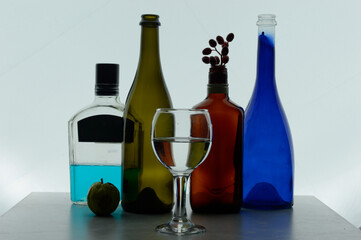 A bottle of liquor, a wine glass with water, and a bottle of water are arranged on a table. 