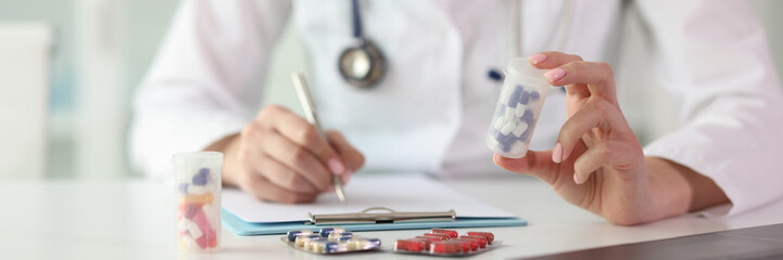 Woman in uniform makes notes looking at pills in bottle