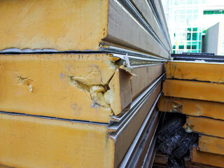 Damaged stack of PUR sandwich panels during unloading at a construction site.