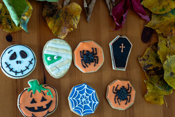 
Homemade Halloween-themed desserts. Various cakes containing the faces of different monsters of the Halloween holiday. Background containing autumn leaves.