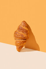 Fresh croissant on yellow  background with hard shadow. Creative diagonal trendy layout and healthy...