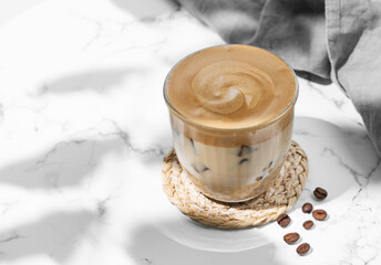 Iced dalgona coffee. Whipped instant coffee in a glass with ice on a marble background