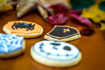 
Homemade Halloween-themed desserts. Various cakes containing the faces of different monsters of the Halloween holiday. Background containing autumn leaves.