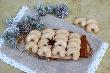 Deutsche traditionelle Weihnachtskekse Vanillekipferl mit Zimtstangen auf einer Baumscheibe...