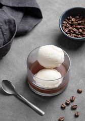Affogato coffee with vanilla ice cream scoops and espresso in a glass on a dark background with coffee beans and spoon.